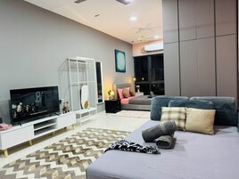 A modern living room with a flat-screen TV, a sofa, a coffee table, and a patterned rug.