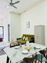 A modern living room with a dining table, green sofa, and a wardrobe.