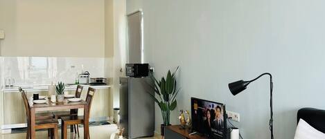 A modern, well-lit room with a bed, a TV, and a dining area.