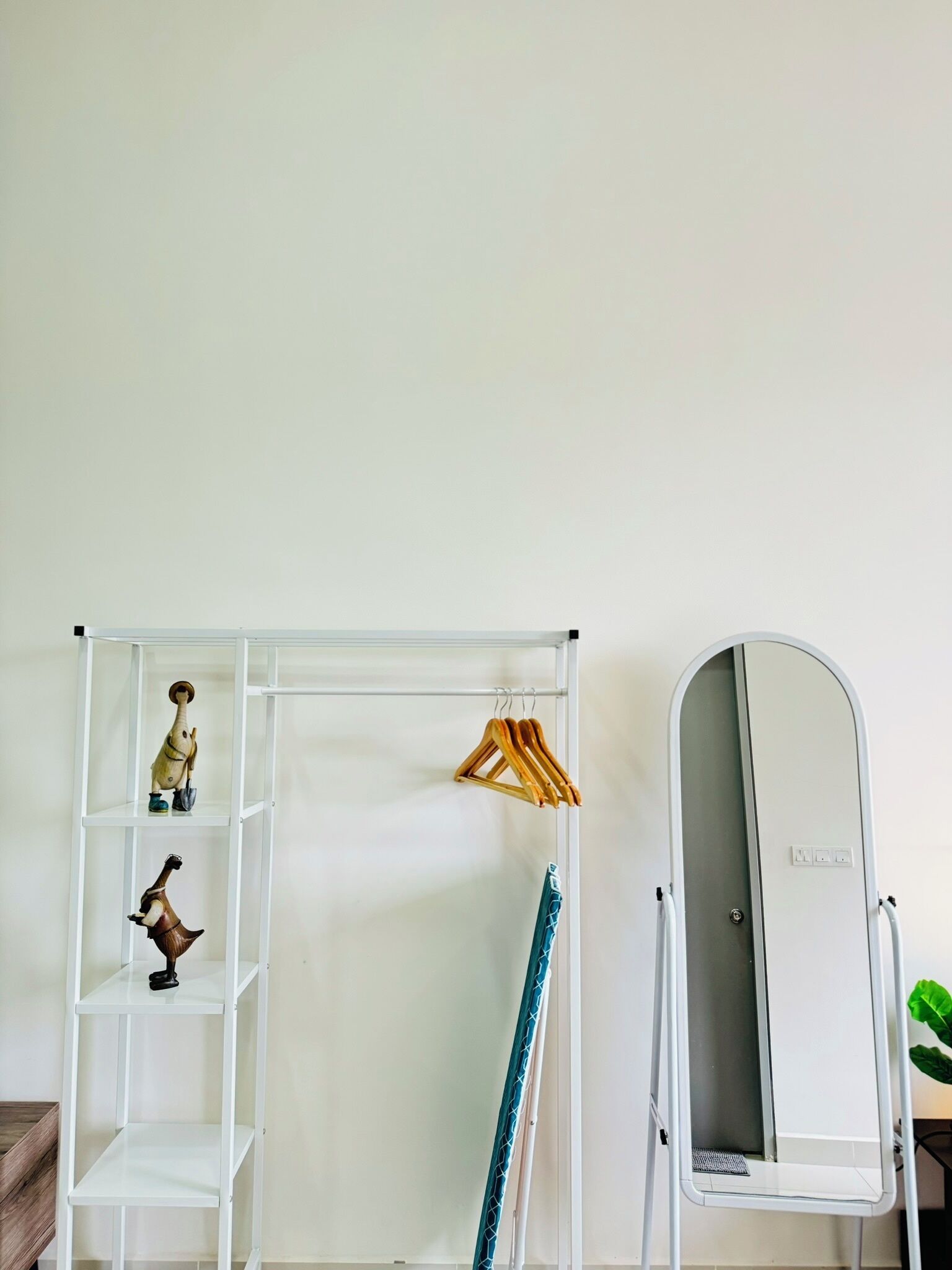 Um guarda-roupa branco com prateleiras, espaço para pendurar roupas e um espelho.