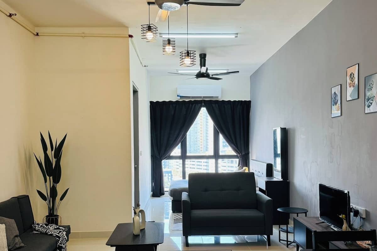 A modern living room with a black sofa, a black armchair, a coffee table, and a TV. There are ceiling fans, pendant lights, and a large window with curtains.
