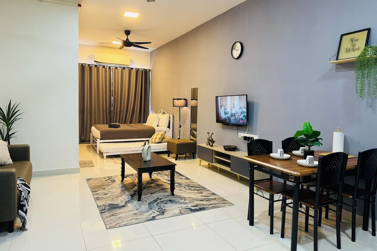 A modern living room with a sofa, a dining table with chairs, a TV, and a ceiling fan.