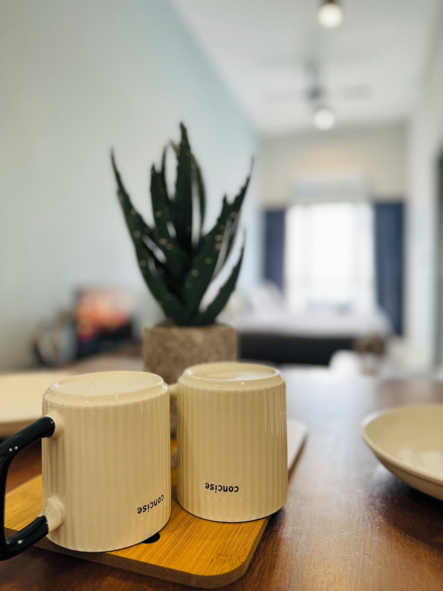 Two white mugs with black handles and the word "Concise" on a wooden tray.