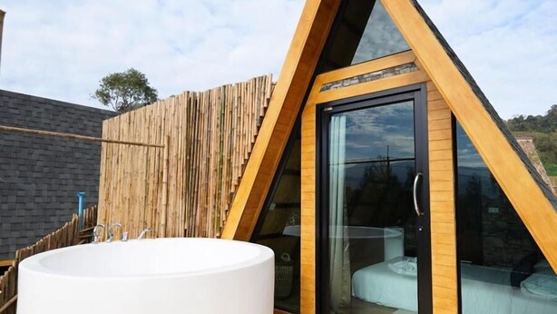A modern, triangular-roofed structure with a large, round, white bathtub on a wooden deck. - RoomQuest Kid Tung Khao (Pak Chong)