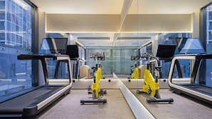 Een moderne sportschool met loopbanden, hometrainers en een spiegelwand.