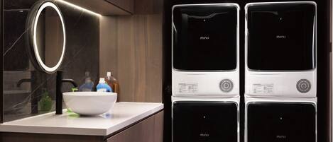 Una cocina moderna con pileta integrada, un espejo y una encimera con un bol y botellas.