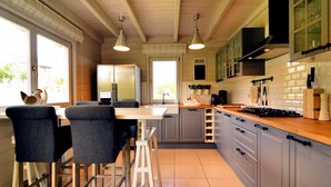 Une cuisine moderne avec un coin repas, comprenant un réfrigérateur, une cuisinière et des tabourets de bar.