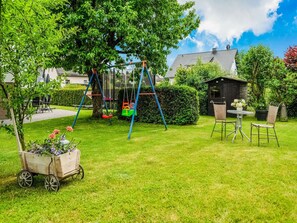 Enjoy a serene outdoor space with a swing set, dining area, and lush lawn.