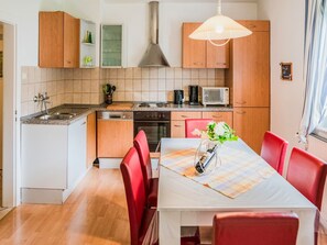 Enjoy meal preparation and dining in this well-equipped kitchen with a stainless steel sink, oven, microwave, and range hood.