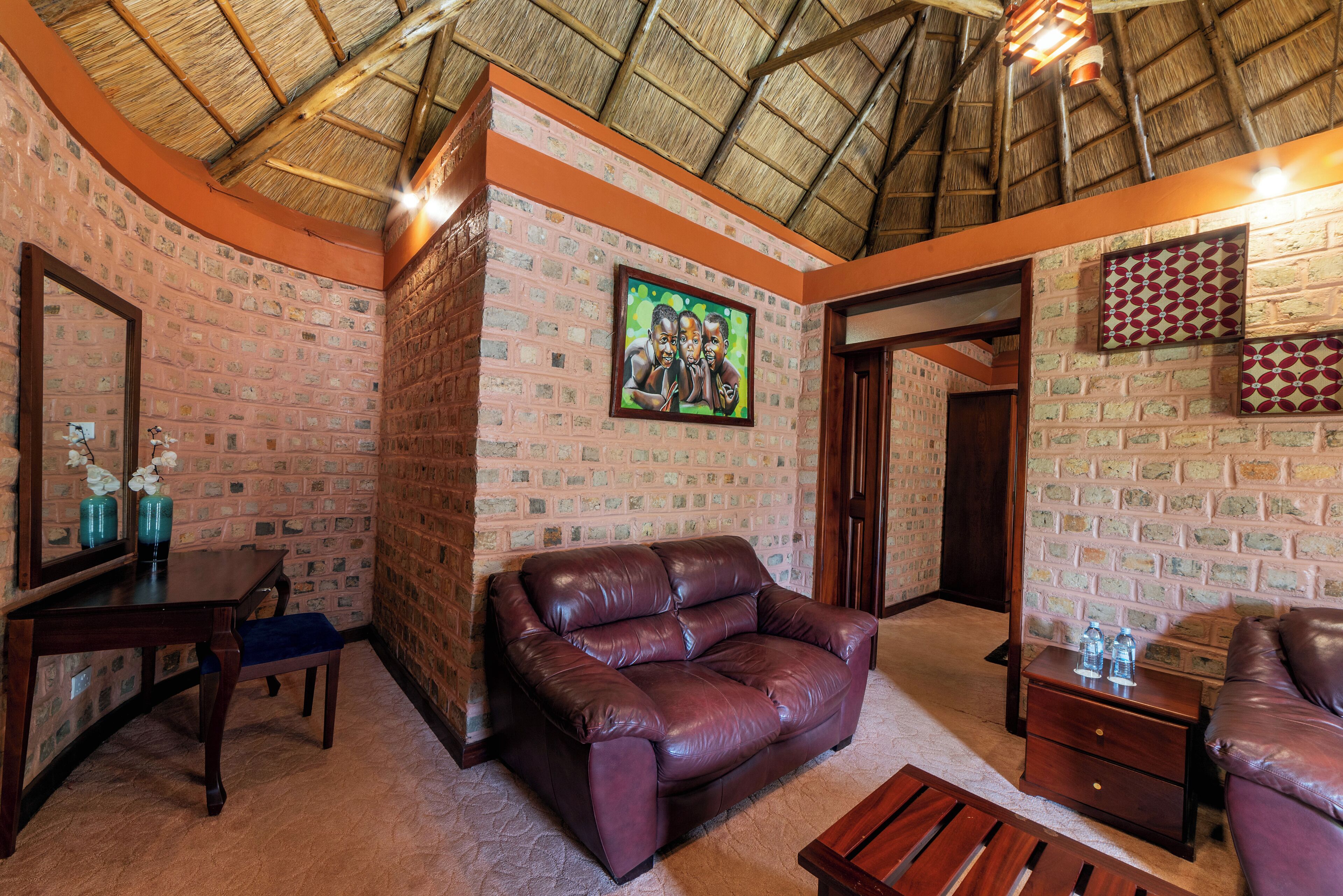 A room with brick walls, a leather sofa, a wooden table, and a mirror.