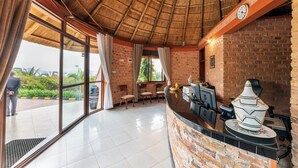 A restaurant with a brick wall, a thatched roof, and a large window. - Masheda Palms Resort (Buloba)