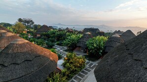 A resort with thatched-roof huts, a paved walkway, and lush greenery. - Masheda Palms Resort (Buloba)