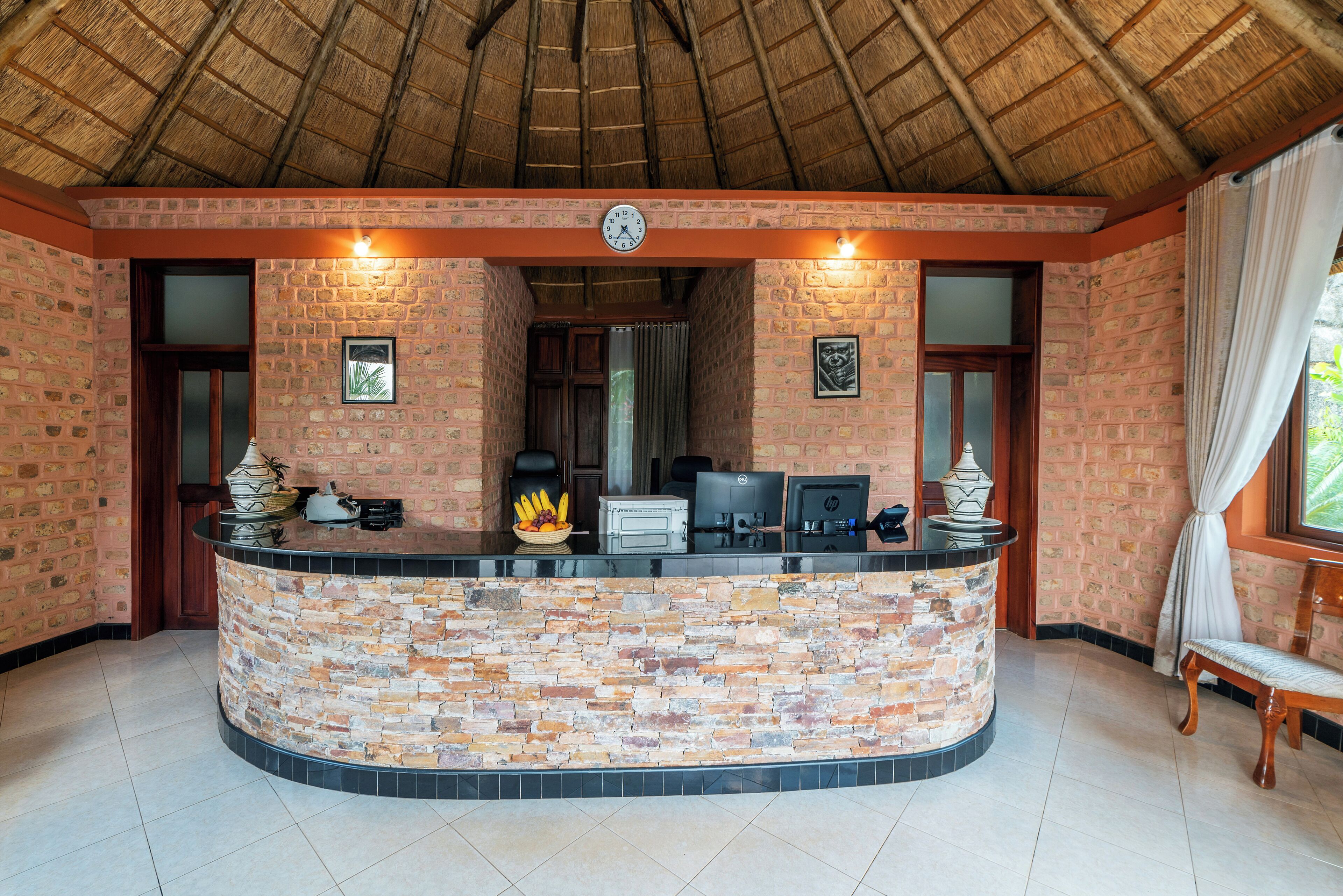 A reception area with a stone counter, a clock, and a window with curtains.