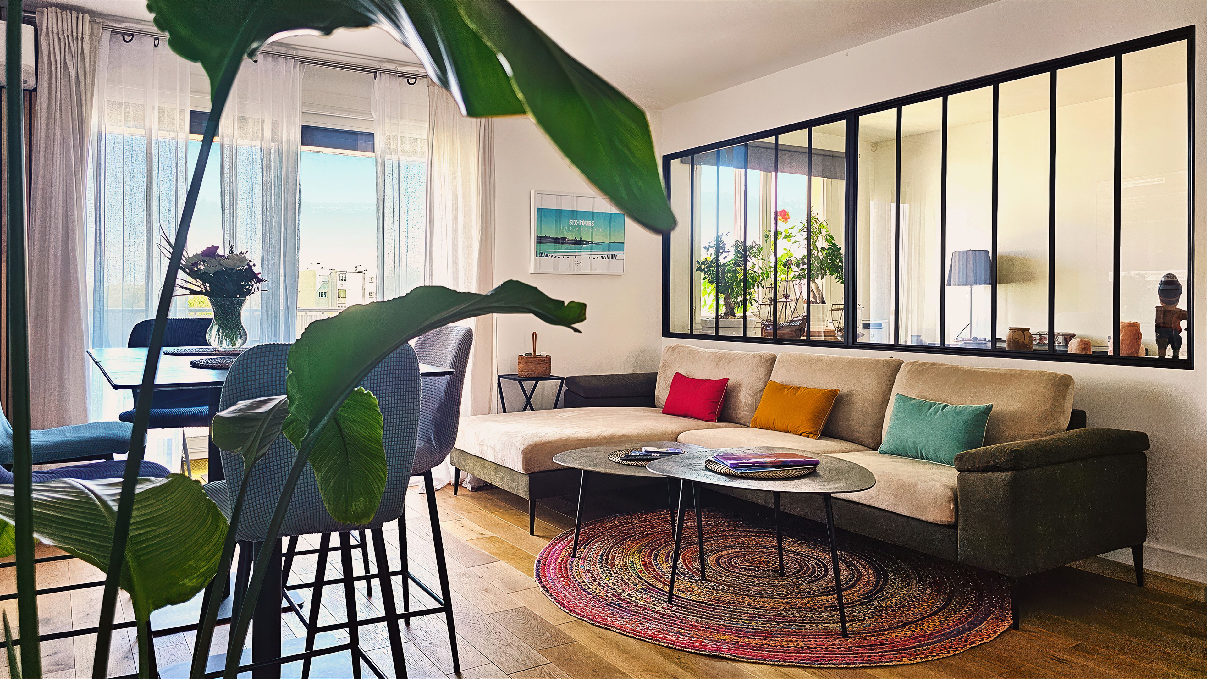 Un salon comprenant un canapé, une table basse et offrant une vue sur l’extérieur grâce à de grandes fenêtres.