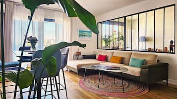 Un salon comprenant un canapé, une table basse et offrant une vue sur l’extérieur grâce à de grandes fenêtres.