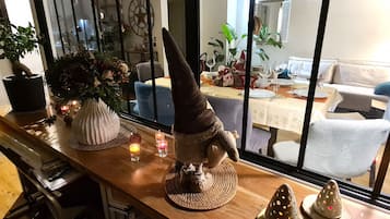 Un coin repas avec une table mise pour le repas, un objet décoratif en forme de cône et une plante en pot posée sur le comptoir.