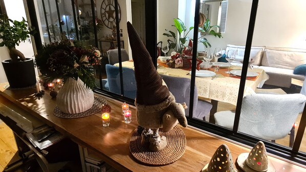 A dining area with a table set for a meal, a decorative conical object, and a potted plant on the counter.