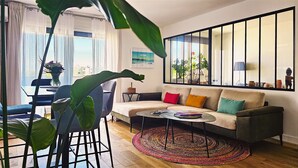 Ein Wohnzimmer mit einer Couch, einem Couchtisch und einer großen Pflanze.