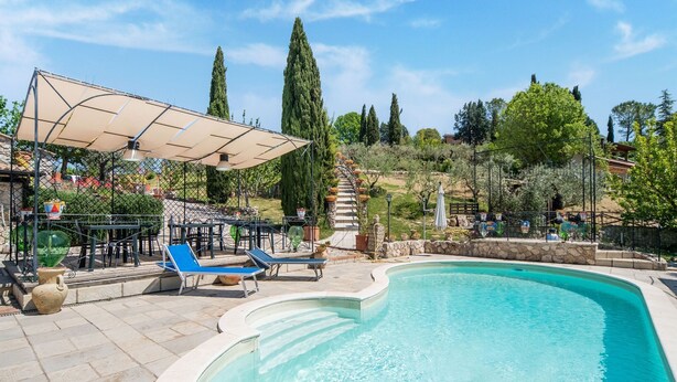 A swimming pool with lounge chairs and a covered patio area.