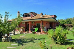 A house with a tiled roof, a stone chimney, and a garden with potted plants and a lawn. - Villa in Monterotondo with Pool & Tiber Views (Monterotondo)