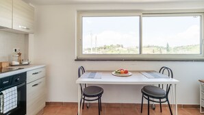A kitchen with a dining table, chairs, and a window with a view of the countryside.