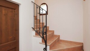 A wooden door, a staircase with a metal railing, and a wall with a picture frame. - Belvilla by OYO Appartamento Yassine (Tredozio)
