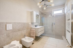 A modern bathroom with a bidet, a sink, a mirror, and a shower enclosure. - Viktor House Salò - 100 mt near lake (Salò)
