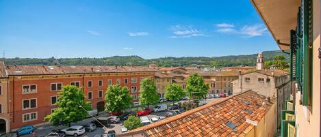 Une vue depuis un balcon donnant sur une rue bordée de voitures garées et d’immeubles.
