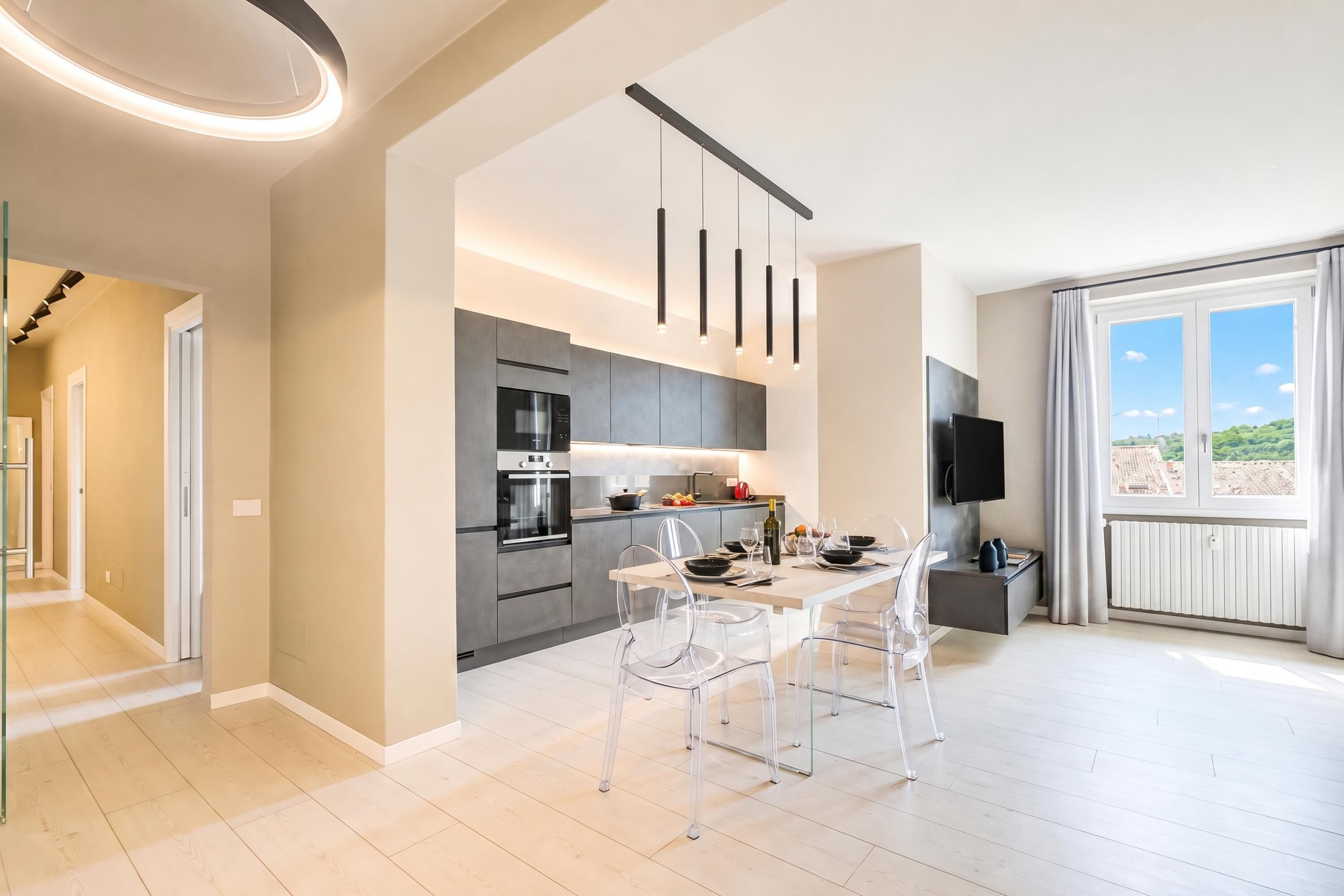 Une cuisine moderne avec un coin repas, un téléviseur et une vue sur l’extérieur.