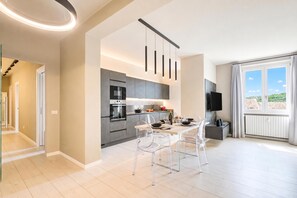 A modern kitchen with a dining area, a TV, and a view of the outdoors. - Viktor House Salò - 100 mt near lake (Salò)