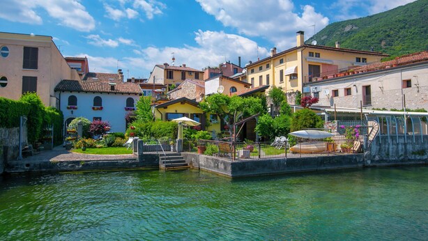 Ein Gebäude am Kanal mit einem kleinen Garten, Stufen zum Wasser und einer überdachten Sitzgelegenheit.