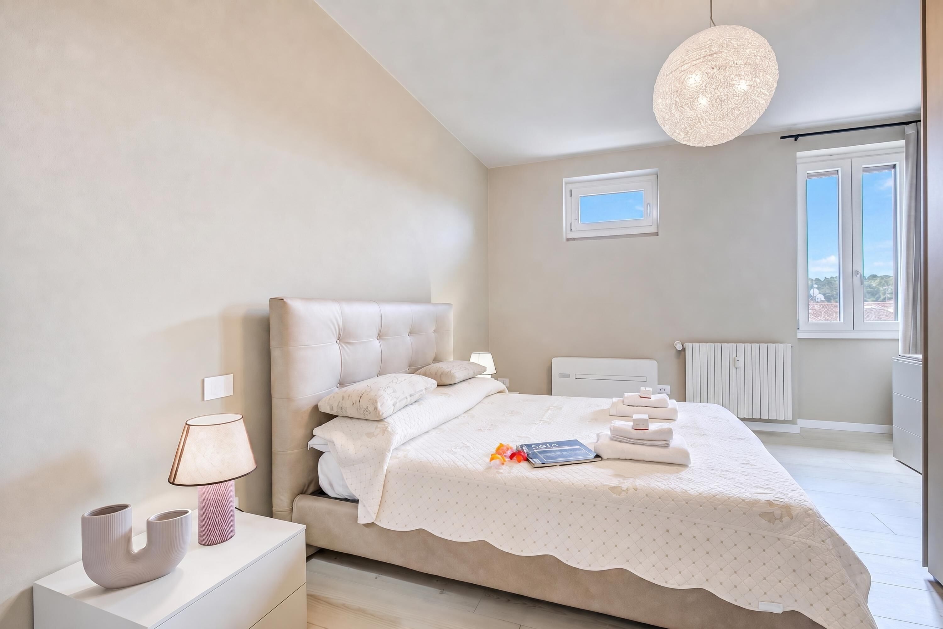 Un dormitorio con cama, lámpara de noche y vistas al exterior.