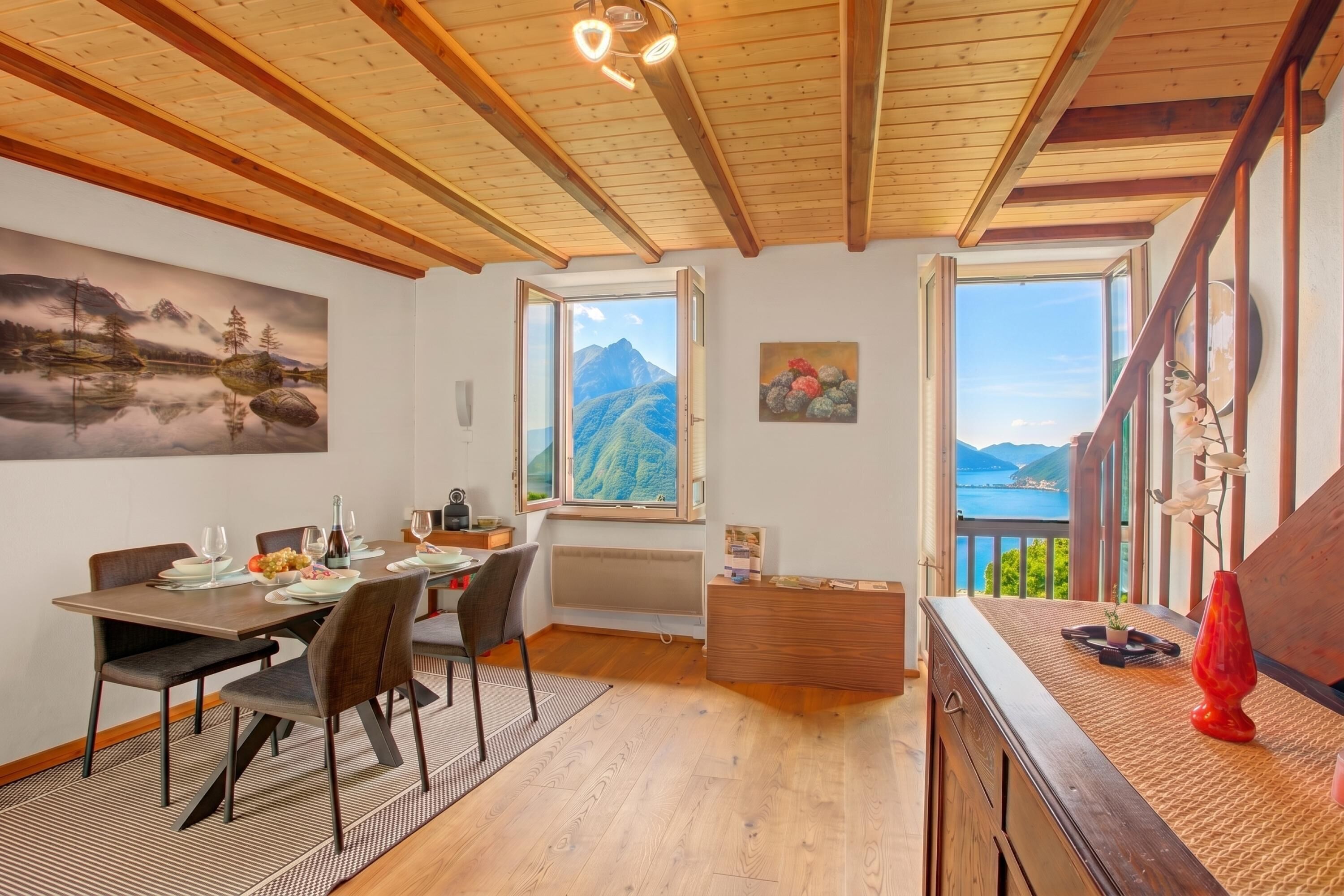 Ein Essbereich mit Holztisch, Stühlen und Blick auf Berge durch ein großes Fenster.