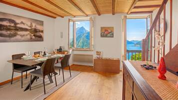Ein Essbereich mit Holztisch, Stühlen und Blick auf Berge durch ein großes Fenster.