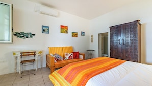 A bedroom with a bed, a wooden chair, a small table, a wardrobe, and wall art. - La Porta Sul Mare - Sea-view Home With Private Beach Access (Diso)