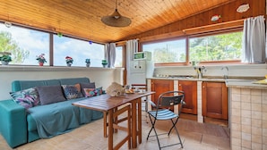 A cozy room with a wooden ceiling, a teal sofa with colorful cushions, a wooden dining table, and a kitchen area with a microwave and sink. - La Porta Sul Mare - Sea-view Home With Private Beach Access (Diso)