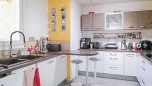 Cozinha moderna com ilha central, eletrodomésticos embutidos e uma parede de destaque amarela.