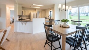 Une cuisine moderne avec des meubles blancs, un îlot central et un coin repas doté de chaises noires.