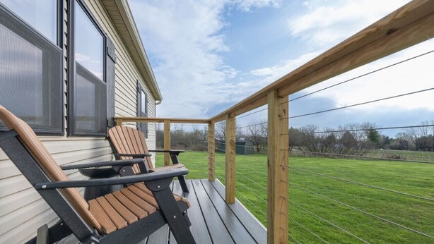 Une terrasse en bois avec une table et deux chaises, donnant sur un champ verdoyant.