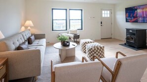 Un salon comprenant un canapé, des fauteuils, une table basse, un téléviseur et une cheminée.