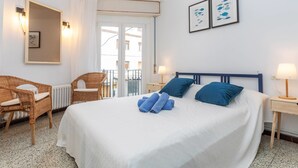 Une chambre d’hôtel avec un grand lit, deux tables de chevet, une chaise, une fenêtre donnant sur un beau paysage et des œuvres d’art accrochées au mur.