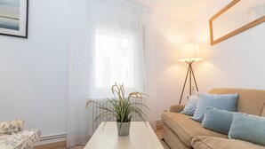 Un salon avec un canapé, une table basse, un lampadaire et une plante en pot.