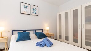 Une chambre d’hôtel comprenant un lit, deux tables de chevet, une armoire et deux tableaux encadrés accrochés au mur.