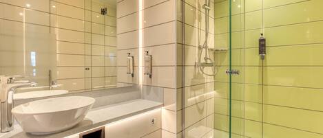 Une salle de bain moderne avec une douche à parois de verre, un grand miroir et un lavabo blanc.