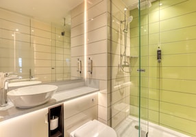 A modern bathroom with a glass-enclosed shower, a large mirror, and a white sink.