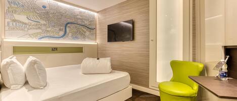 Une chambre d’hôtel avec un lit, une chaise vert vif, un téléviseur à écran plat et une carte accrochée au mur.