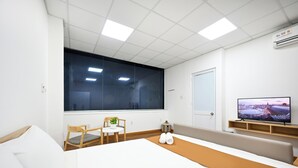 Una habitación de hotel con cama, televisión, ventana, silla y una pequeña mesa.