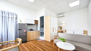 Un espacio habitable compacto con kitchenette, zona de comedor y sofá.