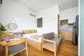 A compact living space with a bed, a sofa, a dining table, and a kitchen area.