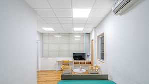 Una habitación pequeña y limpia con cama, escritorio, dos sillas, televisión y ventana.
